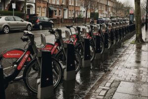 Image of a row of hire cycles in a grey, wet urban street.