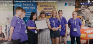 A woman gives a prize to a group of school pupils wearing purple t-shirts