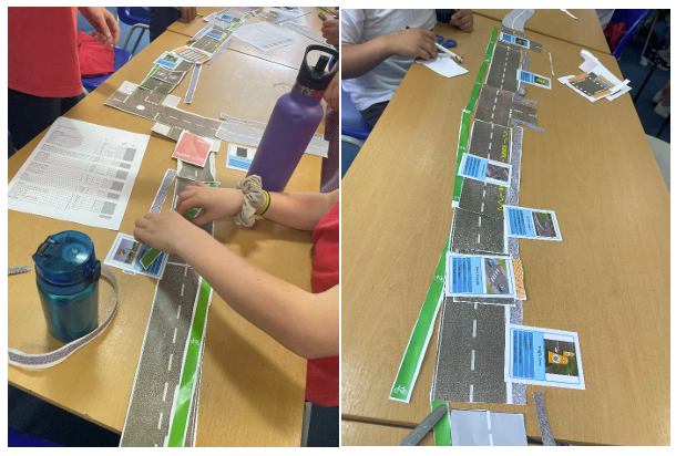 Two images of a long oblong school desk with a model road running up the middle length of the desk. Children are just out of picture (you can see their hands on the model.) they are annotating the road with notes and images of where improvements could be made to safety and accessibility