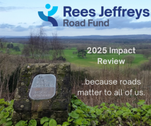Rees Jeffreys Road Fund 2025 Impact Review because roads matter to all of us.... wording in shown against a vista of green rolling hills and vegetation with a cloudy sky on the horizon. There is a square stone monument with a metal plaque that says this amenity is provided for you by the Rees Jeffreys Road Fund
