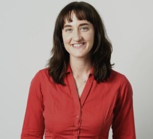 Photo of Rees Jeffreys Road Fund MSc Bursary recipient Seren Rayment who wears a red shirt and has long dark hair.